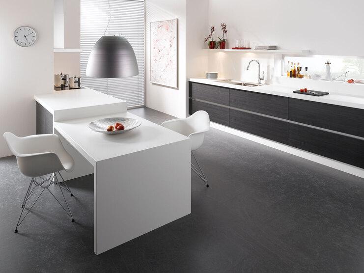 Impression einer einzeiligen Küchengestaltung in schwarz-weiß mit Esstisch für Zwei
